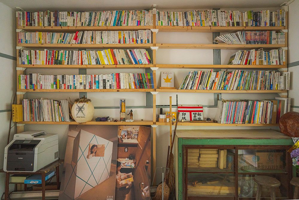 写真：壁一面の本棚。様々な本がラフに並んでいる。